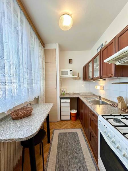 A kitchen in a 2-room apartment with a kitchen unit, a gas stove, and a floor with a wooden decor.
