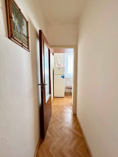 A hallway with a door frame, a wooden decor floor, and a painting on the wall.