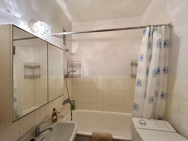 Bathroom with a shower, mirror, and washing machine in a 2-room apartment.