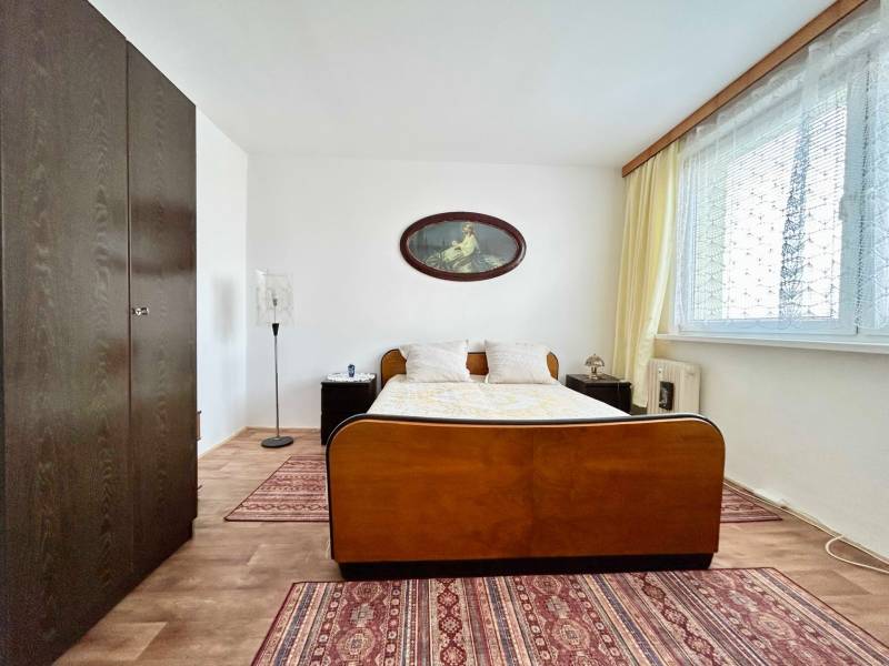 Bedroom in a 2-room apartment with a double bed, wardrobe, and floor with a wooden decor.