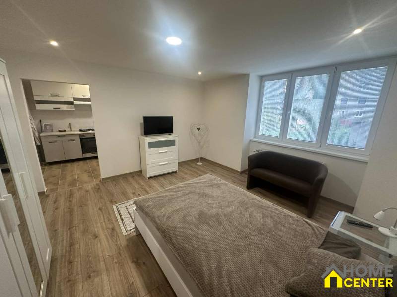 Living room in a one-room apartment with a wooden decor floor and a view outside.