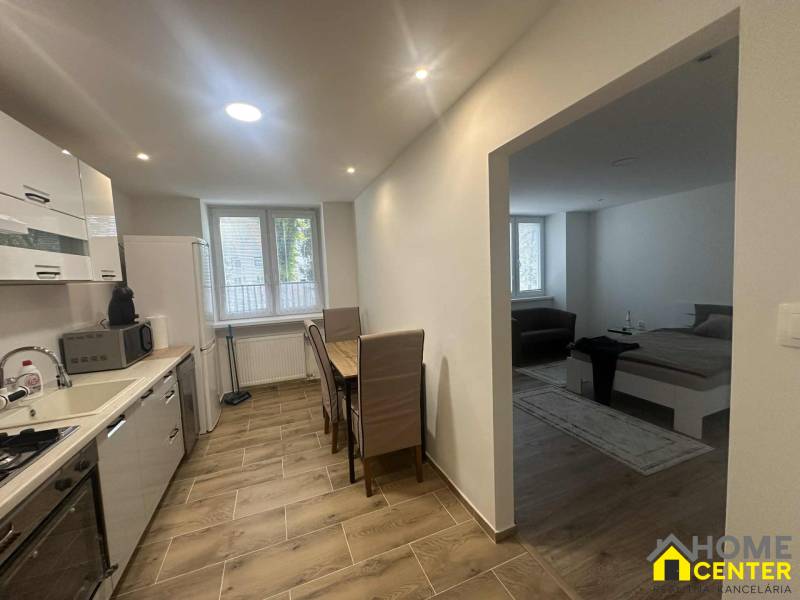 A kitchen in a studio apartment with appliances and a wood-patterned floor.
