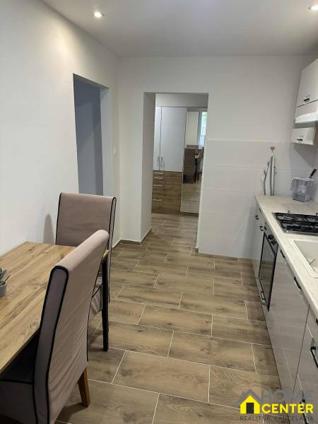 A kitchen with a table and a wooden floor decor in a studio apartment.