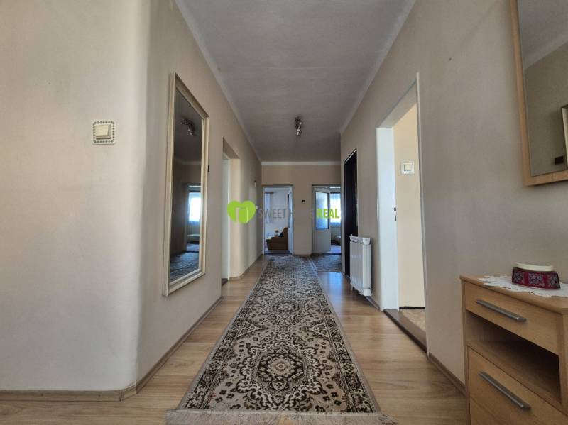 A hallway in a family house with a wooden decor floor and a carpet.