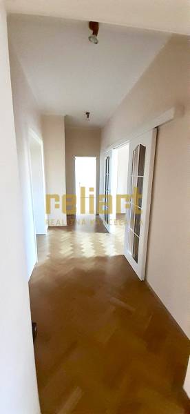 A hallway with light walls and a floor with a wood decor in a 4-room apartment.
