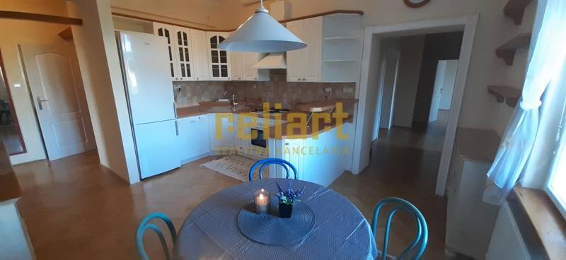 A kitchen in a 4-room apartment with a wood-patterned floor, a dining table, and a white kitchen unit.
