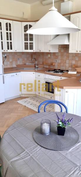 A kitchen with white cabinets, a wooden decor floor, and a table in a 4-room apartment.