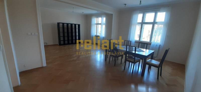 Bright living room with a table and chairs, wooden decor flooring in a 4-room apartment.
