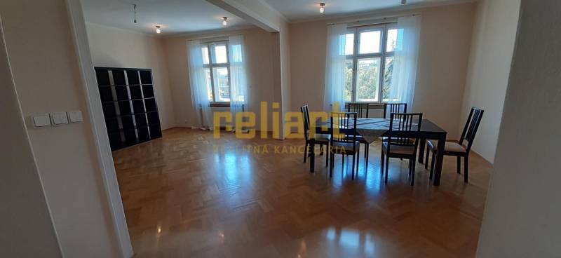 Dining area with a large table and a wooden decor floor in a 4-room apartment.