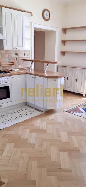 A kitchen in a 4-room apartment with a wooden decor floor and white cabinets.