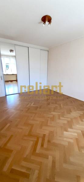 A room with a wooden decor floor and a sliding wardrobe in a 4-room apartment.