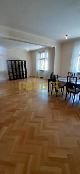 Spacious living room with a table and chairs, wood-decorated flooring, 4-room apartment.