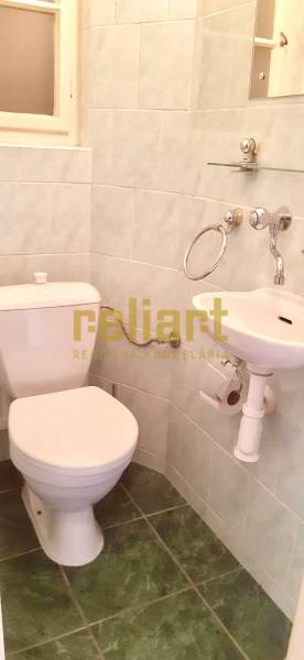 Bathroom in a 4-room apartment with a sink, toilet, and green tiles.