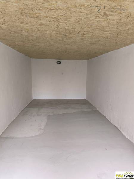 White garage with a wooden ceiling and concrete floor on M. R. Štefánika Street in Detva.
