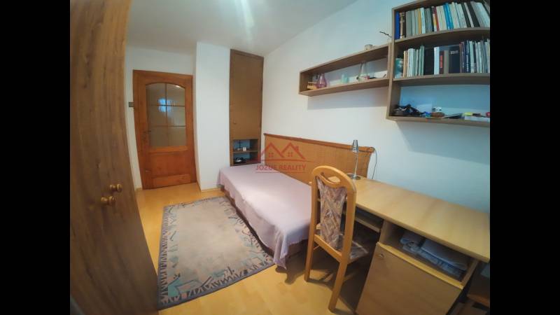 A room in a family house with a desk, a sofa set, and shelves.
