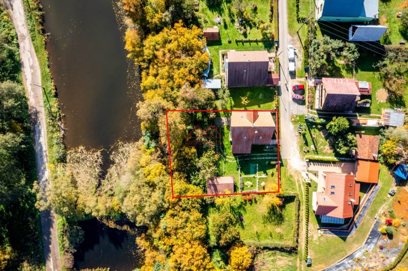 A family house in Medzev by the river and road, surrounded by greenery and neighboring houses.