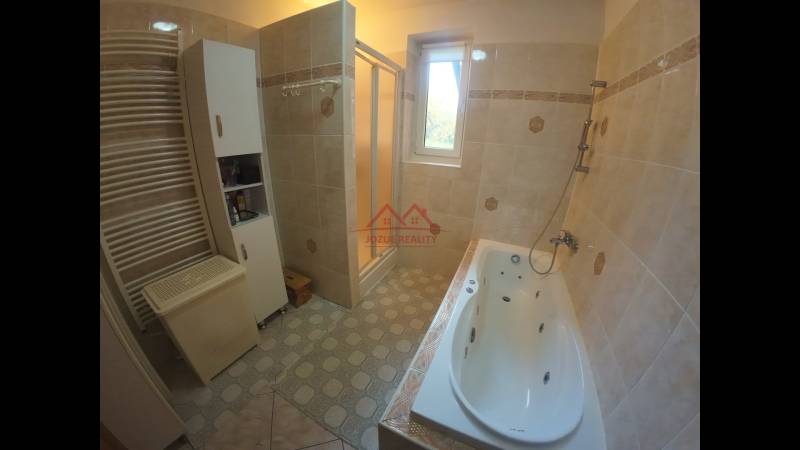 Bathroom with a bathtub, shower, cabinet, and radiator in a family house.
