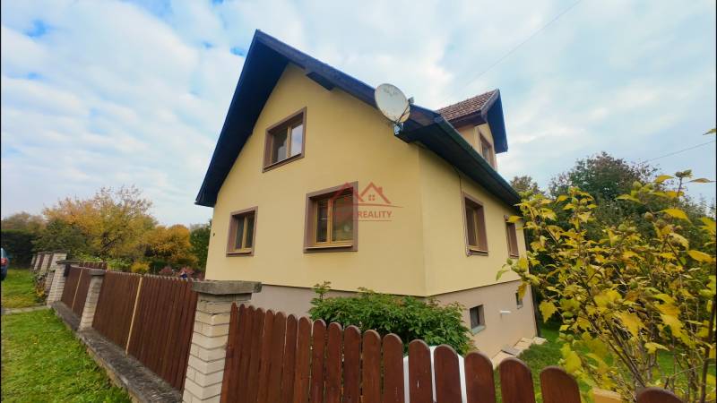 A family house in Medzev with a wooden fence and a garden, in an autumn setting.