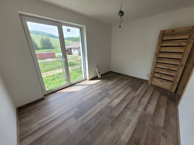 A room in a family house with a wooden decor floor and large windows.