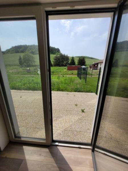 An open door leading to the terrace with a view of the garden, in a family house.