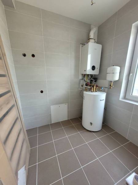 Technical room with a boiler and a gas boiler in a family house. The walls are tiled.
