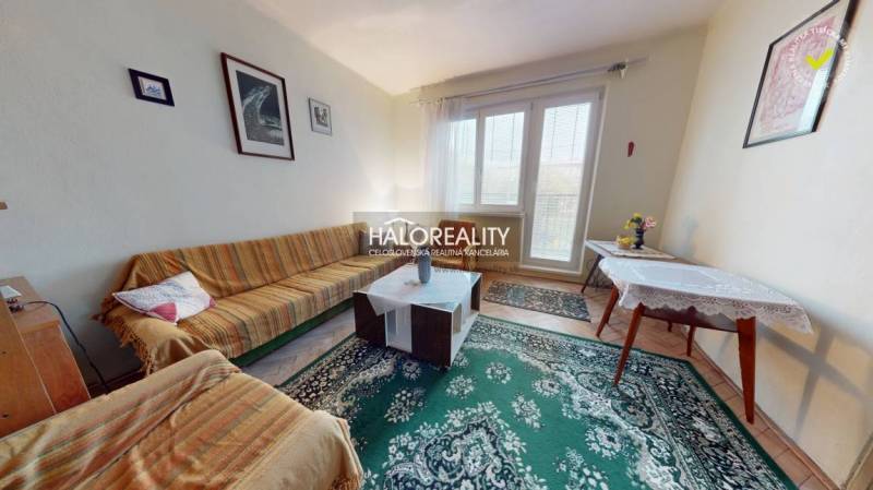 Living room in a 3-room apartment with a colorful sofa and a decorative carpet.