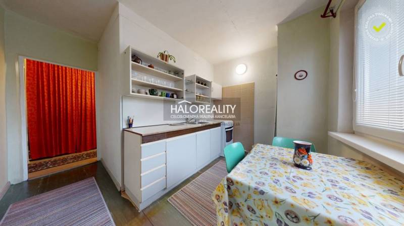 A kitchen in a 3-room apartment with light furniture and a table with a patterned tablecloth.