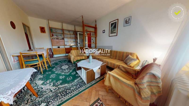 Living room with a sofa and carpet, wooden decor flooring in a 3-room apartment.