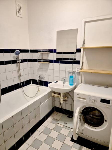 Bathroom with a bathtub, washing machine, and sink in a studio apartment.