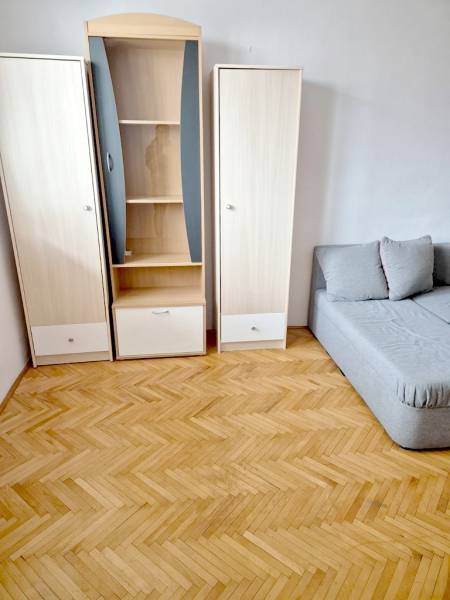 Interior of a 1-room apartment with wooden decor, cabinets, and a sofa.