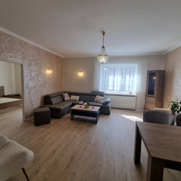 A bright living room with a sofa, table, and a view of the bedroom in a 3-room apartment.