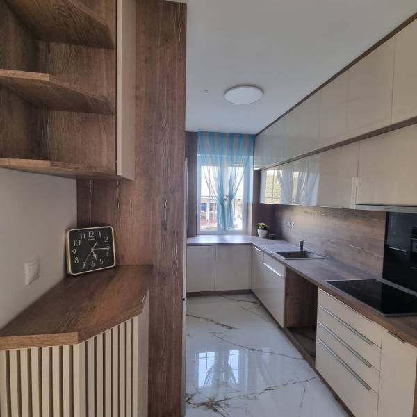 A stylish kitchen with wooden details, a spacious countertop, and modern equipment for a 3-room apartment.