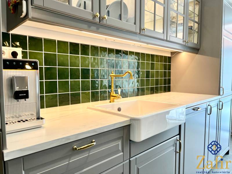 A kitchen in a family house with ceramic tiles and a sink.