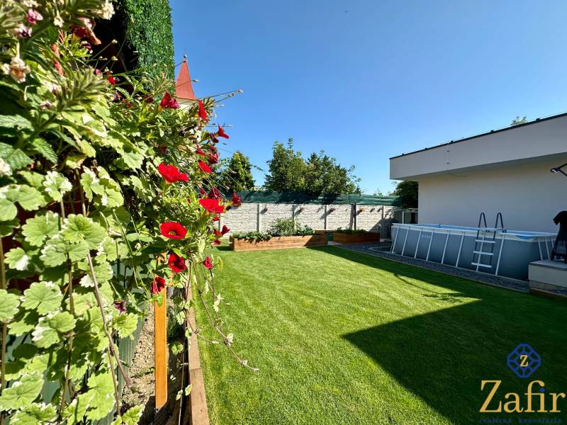 A garden at a family house in Šelpice with a swimming pool and colorful flowers.
