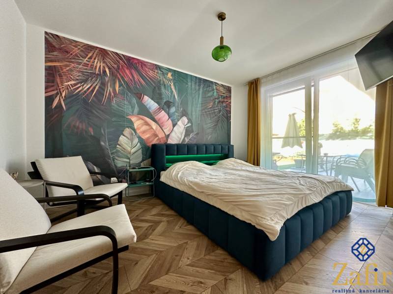 A bedroom with rich wallpaper, a wooden decor floor, a large window with a view.