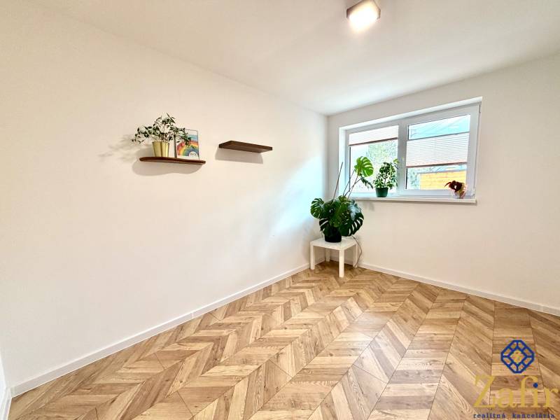 White room in a family house with wooden decor and plants on the shelves.
