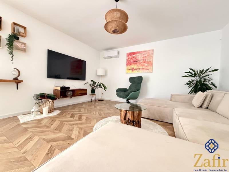 A spacious living room with a wooden-patterned floor and a comfortable corner sofa in a family house.