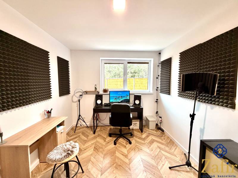 Recording studio in a family house with a wood-patterned floor and acoustic panels.