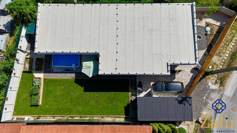 Aerial view of a family house in Šelpice with a garden and a swimming pool.