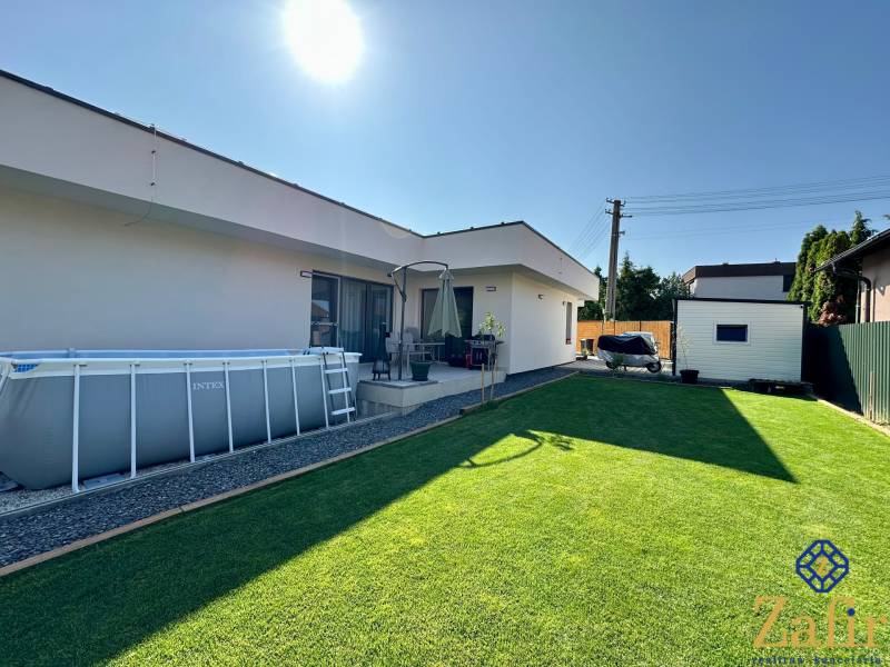 A family house in Šelpice with a garden, an above-ground pool, and a lawn.