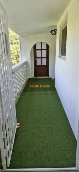 The balcony of a 2-room apartment with a green carpet and wooden doors.