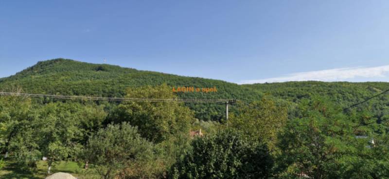 A wooded hill surrounded by greenery in the vicinity of the town Hollóháza, clear sky.