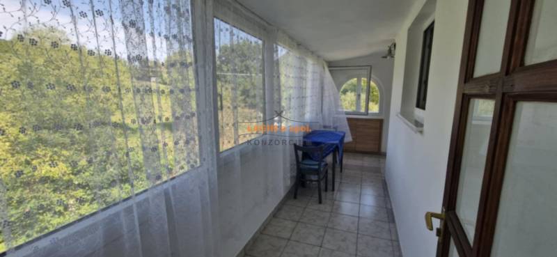 A glazed terrace in a 2-room apartment with a curtain and a view of nature.