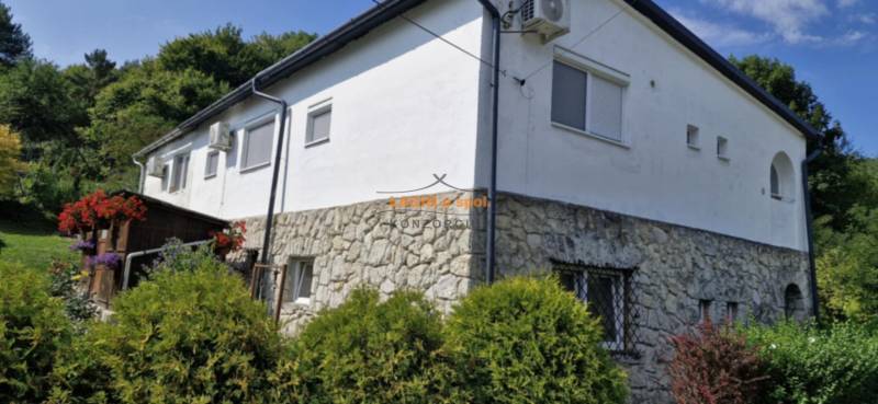 A stone house with a white facade surrounded by greenery in Hollóháza.
