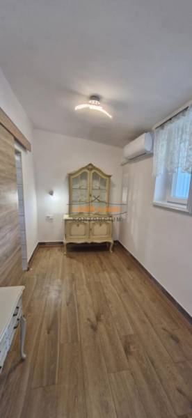 A room with a wooden decor floor in a 2-room apartment, decorative furniture, and air conditioning.