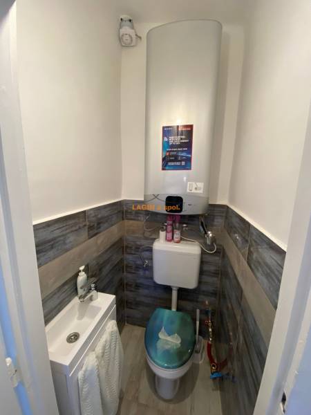 Compact toilet with a sink and floor with wood decor in a 2-room apartment.