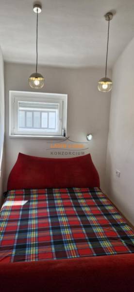 Small bedroom of a two-room apartment with a bed and hanging lights.