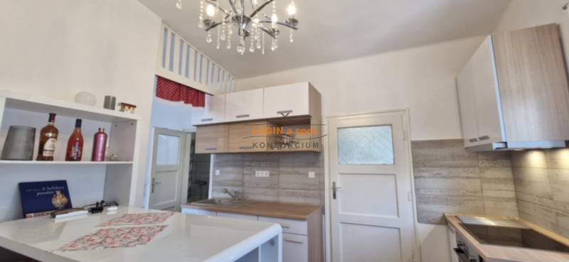 A kitchen in a 2-room apartment with a chandelier, wooden cabinets, and decorative elements.