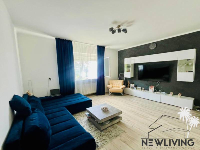 Living room in a three-room apartment with a wood-patterned floor and a dark blue couch.