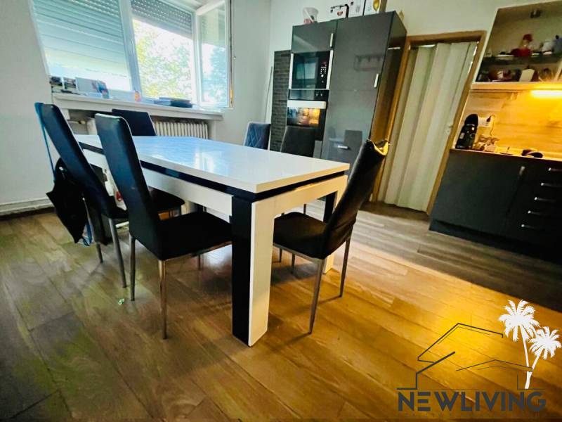 A kitchen in a 3-room apartment with a wooden decor floor and dark furniture.